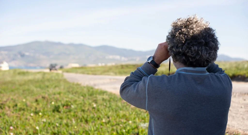 Birdwatchers with binoculars and field guides observing birds in their natural habitat